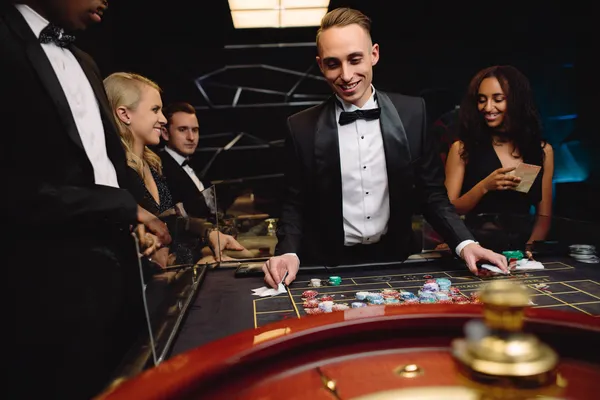 A woman in a luxurious green gown next to an ornate roulette wheel, capturing the upscale casino mood of KWIKIBET.