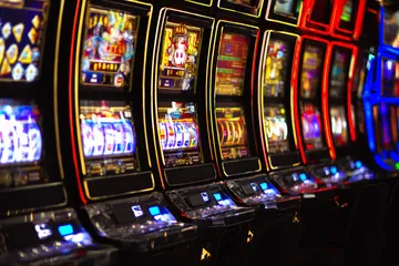 A woman smiling by bright slot machines showing lucky symbols, showcasing the exciting slot offerings at KWIKIBET.